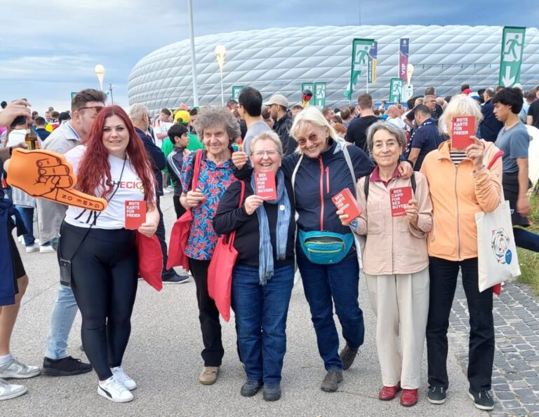 Hier ist das Titelbild zu sehen. Es zeigt die Aktivist*innen der Aktionsgruppe Gleichstellung Bayern (AGGB) vor der Allianz-Arena in München.