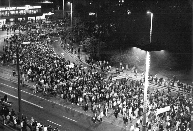 Hier ist das Titelbild zu sehen. Es zeigt die Teilnehmenden einer Demonstration in Leipzig im Oktober 1989