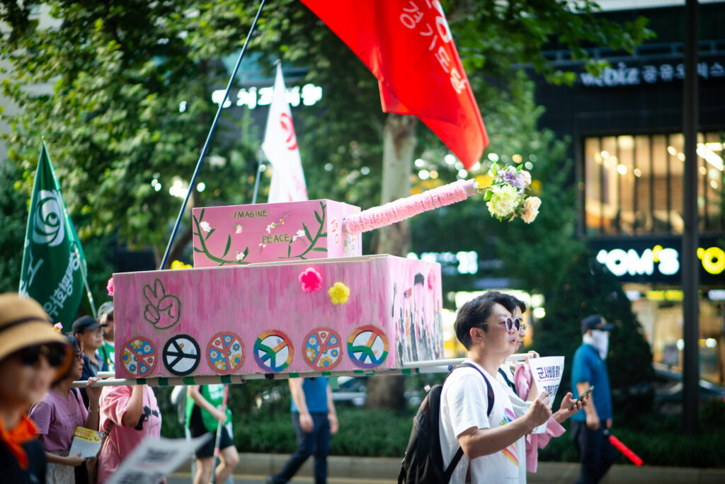 Hier ist Bild 3 zu sehen. Es zeigt einen rosa Friedenspanzer auf einer Demonstration in Seoul, Südkorea